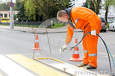 Road worker marking pedestrian crossing line Stock Photo