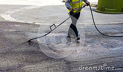 Road worker spraying bitumen emulsion Stock Photo