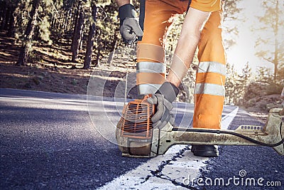 Road worker starting a brushcutter Stock Photo