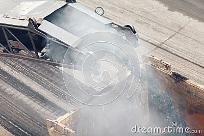 Road works. Asphalt removing machine loading powdered asphalt on the truck Stock Photo