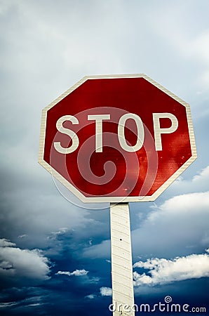 Roadside red stop sign on a cloudy background. Stock Photo