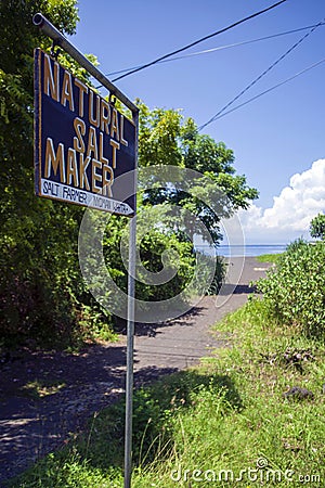 A roadside sign marking the location of a Natural Salt Maker in Goa Lawah, Bali, Indonesia. Editorial Stock Photo