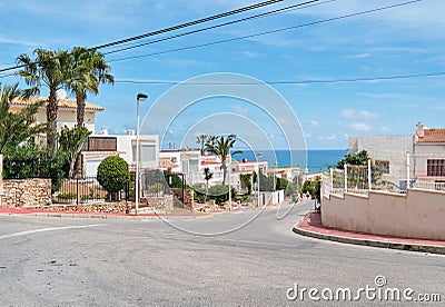 Roadside view to the empty road leading to Mediterranean Sea, coastal summer villas residential houses, blue cloudy sky, Stock Photo