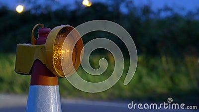 Roadworks cone flashing on UK motorway at night with traffic passing Stock Photo