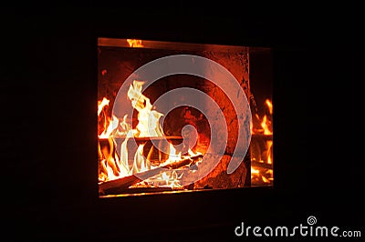 Roaring flames in a modern fireplace with shiny slate framing Stock Photo