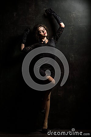 Roaring Twenties. Woman portrait in the style of Gatsby. Low key. Beautiful young woman in a lace black dress, posing sensually. Stock Photo