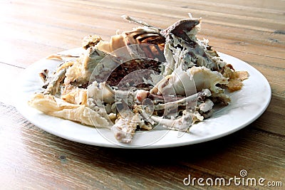 Roast chicken carcass remains on a plate on a wooden table Stock Photo