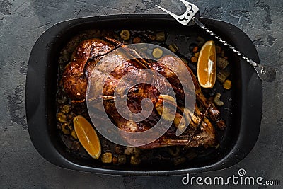 Roast duck with oranges and apples in a frying pan, dark photo, top view Stock Photo