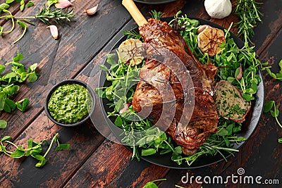 Roast Lamb leg with mint sauce, rosemary and garlic. on black plate, wooden table Stock Photo