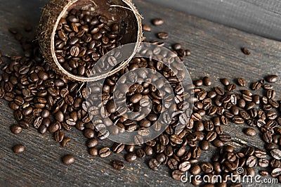 Roasted arabica coffee beans scattered on a wooden table from a coconut. Fresh coffee beans. Stock Photo