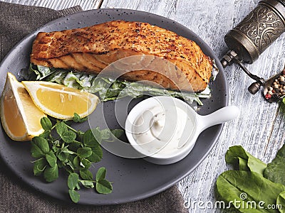 Roasted baked salmon fillet with lemon, white sauce and spinach close up Stock Photo