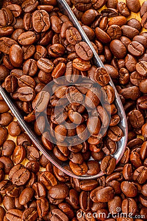 Roasted Brown coffee beans in metal scoop background Close Up Stock Photo