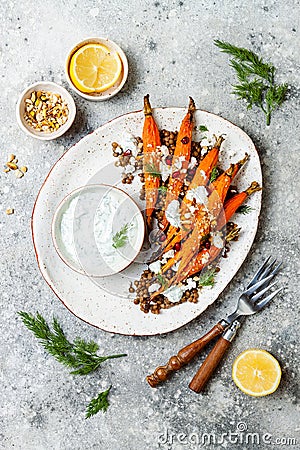 Roasted carrots lentil salad with feta, herb yogurt and dukkah on a light concrete background. Vegetarian food. Stock Photo