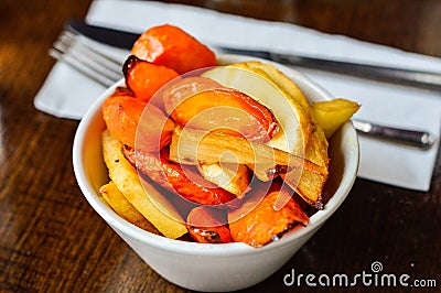 Roasted Carrots and Parsnips in a Bowl Placed at Restaurant Table Stock Photo