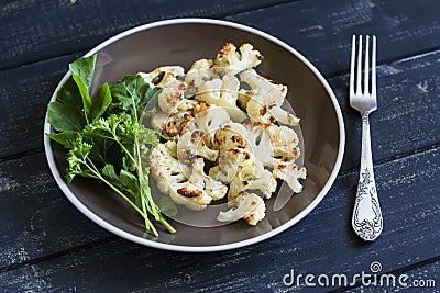 Roasted cauliflower and fresh green salad on a brown plate Stock Photo