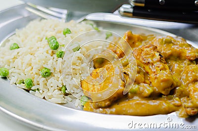 Roasted chicken breast pieces in a mildly spiced coconut curry sauce with fried rice with peas and egg Stock Photo