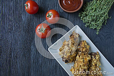 Roasted chicken drumsticks on a plate. Breaded chicken drumsticks, fried chicken. Dark wooden background Stock Photo