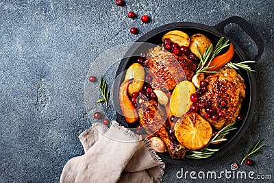 Roasted chicken legs with root vegetables, lemon, garlic, cranberry and rosemary on pan Stock Photo