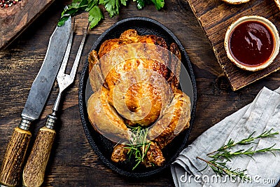 Roasted chicken with rosemary served on black plate with sauces on wooden table, top view. Stock Photo