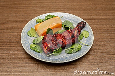 Roasted chicken thigh in Hindu tandoori style with a good piece of sweet potato garnish Stock Photo