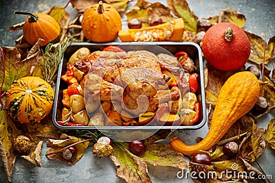 Roasted chicken or turkey garnished with pumpkins, pepper and potatoes. Served on a rustic table Stock Photo