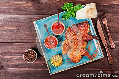 Roasted Chicken or turkey with spices, lemon, tomato sauce, basil and pita bread on plate on dark wooden background. Thanksgiving Stock Photo