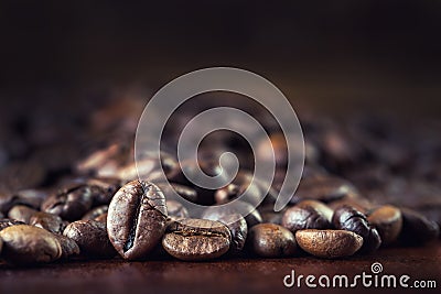 Roasted coffee beans spilled freely on a wooden table. Stock Photo