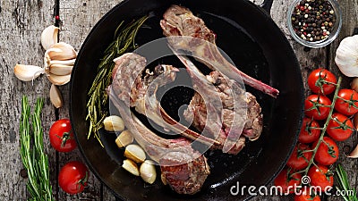 Roasted lamb ribs with rosemary, tomatoes, garlic on pan on dark rustic wooden background, top view, long width banner Stock Photo