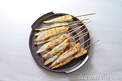 Roasted Mediterranean chicken skewers with herbs and spices, finger food snack for a festive New Year party on a dark purple plate Stock Photo