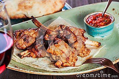 Roasted rabbit with herbs, tomato sauce and glass of wine on a plate. Hot Meat Dishes. Stock Photo