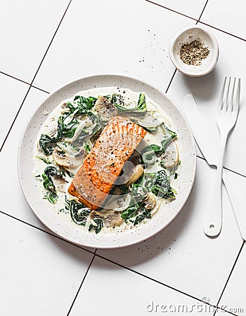 Roasted salmon with creamy spinach mushrooms sauce on a light background, top view. Salmon florentine Stock Photo