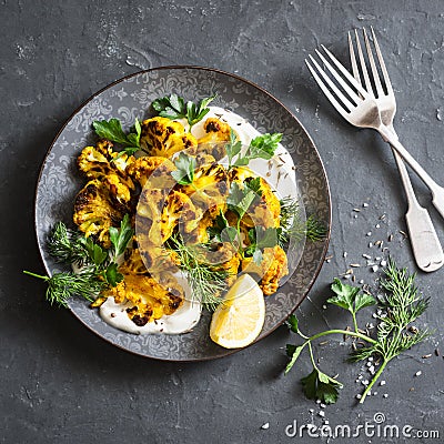 Roasted turmeric cauliflower with greek yogurt dressing on a dark background Stock Photo