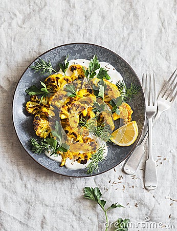 Roasted turmeric cauliflower with greek yogurt dressing. Delicious healthy food on a grey background Stock Photo