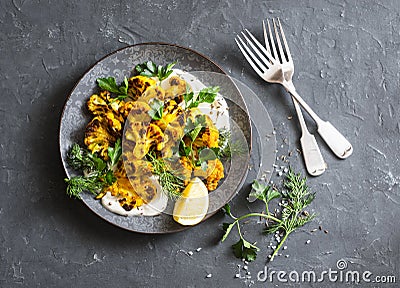 Roasted turmeric cauliflower with greek yogurt dressing. Delicious healthy snack on a dark background Stock Photo