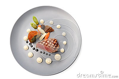 Roasted veal, morels, vegetables and a fried potato stuffed with onion seeds on a blue plate, festive garnished gourmet dish Stock Photo