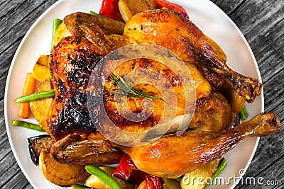 Roasted whole chicken, potatoes, baby carrots, eggplants, green Stock Photo