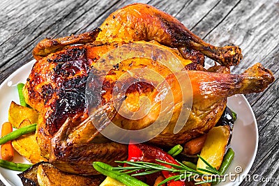 Roasted whole chicken, potatoes, baby carrots, eggplants, green Stock Photo