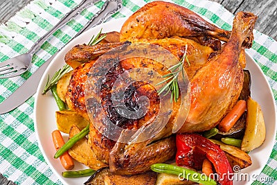 Roasted whole chicken, potatoes, baby carrots, eggplants, green Stock Photo