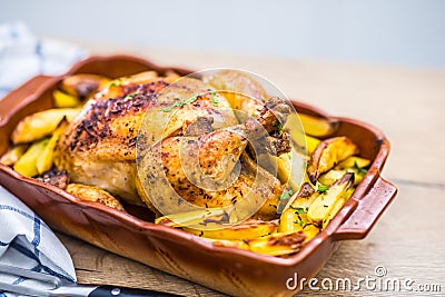 Roasted whole chicken with potatoes in baking dish. Tasty food at home on the kitchen counter Stock Photo