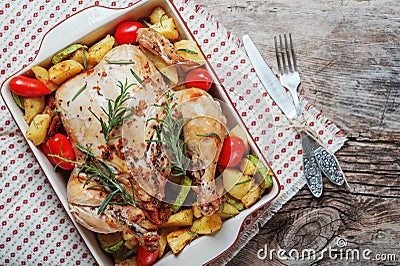 Roasted whole chicken stuffed with vegetables, tomatoes potato pepper and rosemary on vintage napkin wooden table background Stock Photo