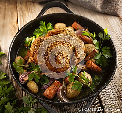 Roasted whole chicken with vegetables in a cast iron pan Stock Photo