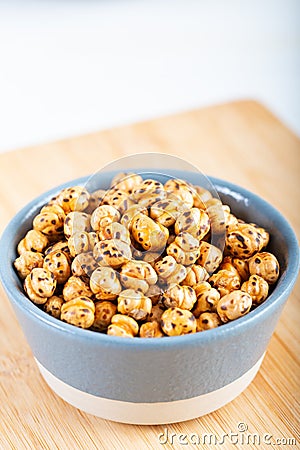 Roasted, yellow chickpeas in ceramic bowl on wooden Stock Photo