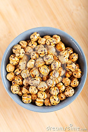 Roasted, yellow chickpeas in ceramic bowl on wooden Stock Photo