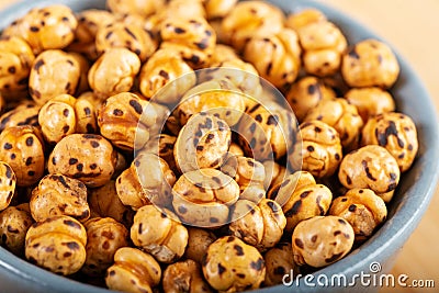 Roasted, yellow chickpeas in ceramic bowl on wooden Stock Photo