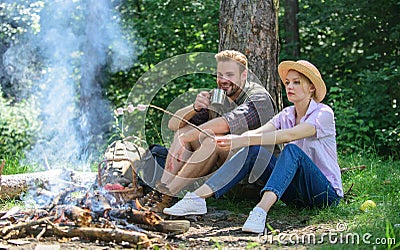 Roasting marshmallows at bonfire. Couple in love camping forest roasting marshmallows. Couple friends prepare roasted Stock Photo