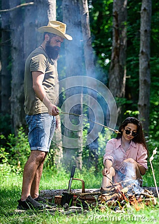 Roasting marshmallows popular group activity around bonfire. Couple in love camping forest roasting marshmallows. Couple Stock Photo