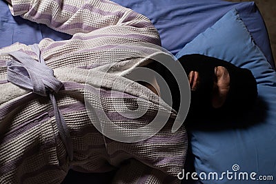 The robber in the mask lies in bed and sleeps. The thief is tired. Night adventure dreams playful concept Stock Photo