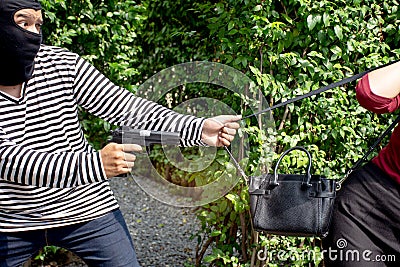 Robber thief criminal with gun standing behind a Asian women and to come nearest for scramble the valuables Stock Photo