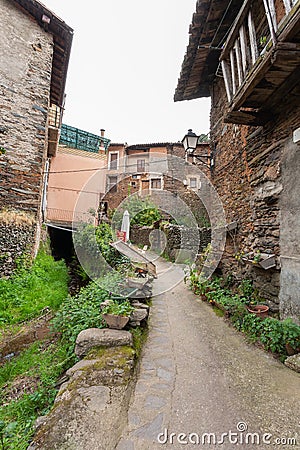 A narrow concrete street with large potted plants next to a stream that flows into the Arrago river Editorial Stock Photo