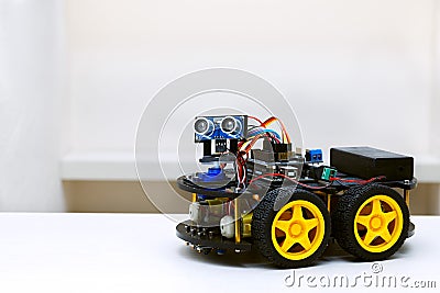 Robot with four wheels stands on a white table Stock Photo